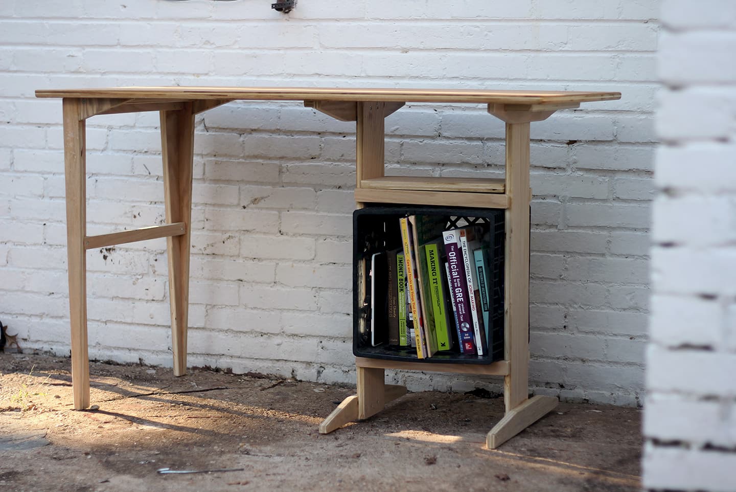 Plywood desk with a milk crate built into it as a shelf.